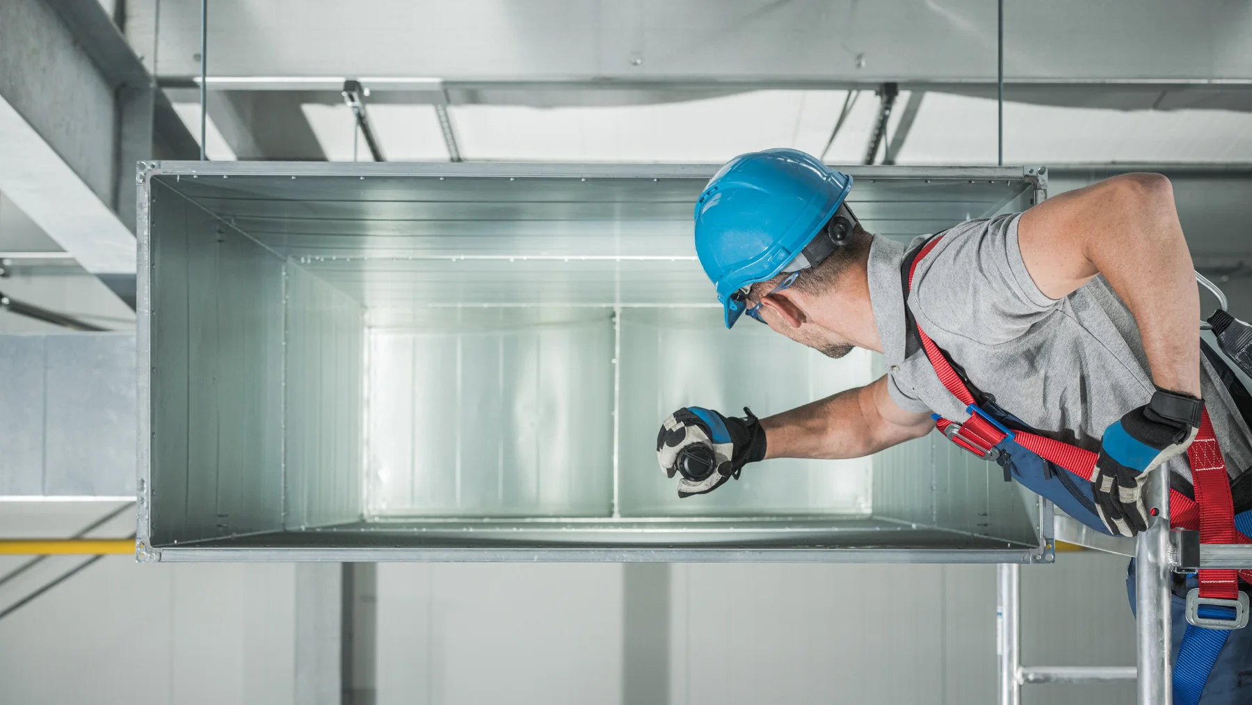 Technician inspecting commercial metal ventilation ductwork