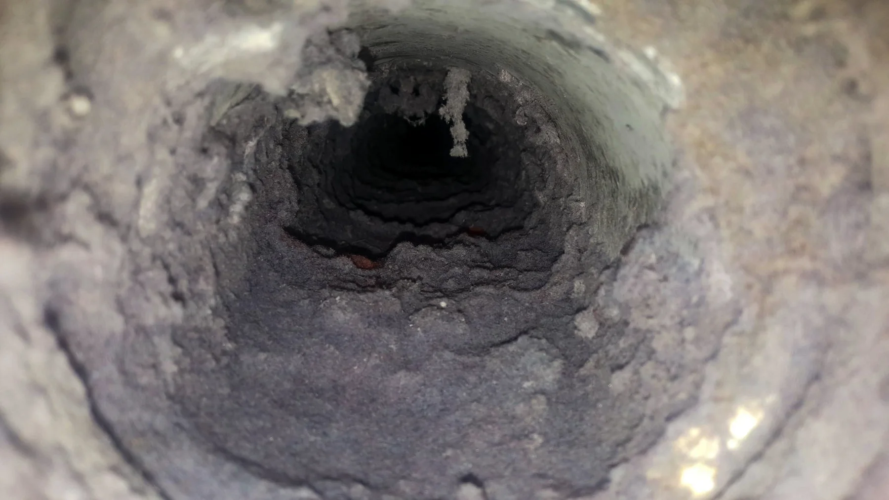 Photograph looking into ductwork with accumulated debris