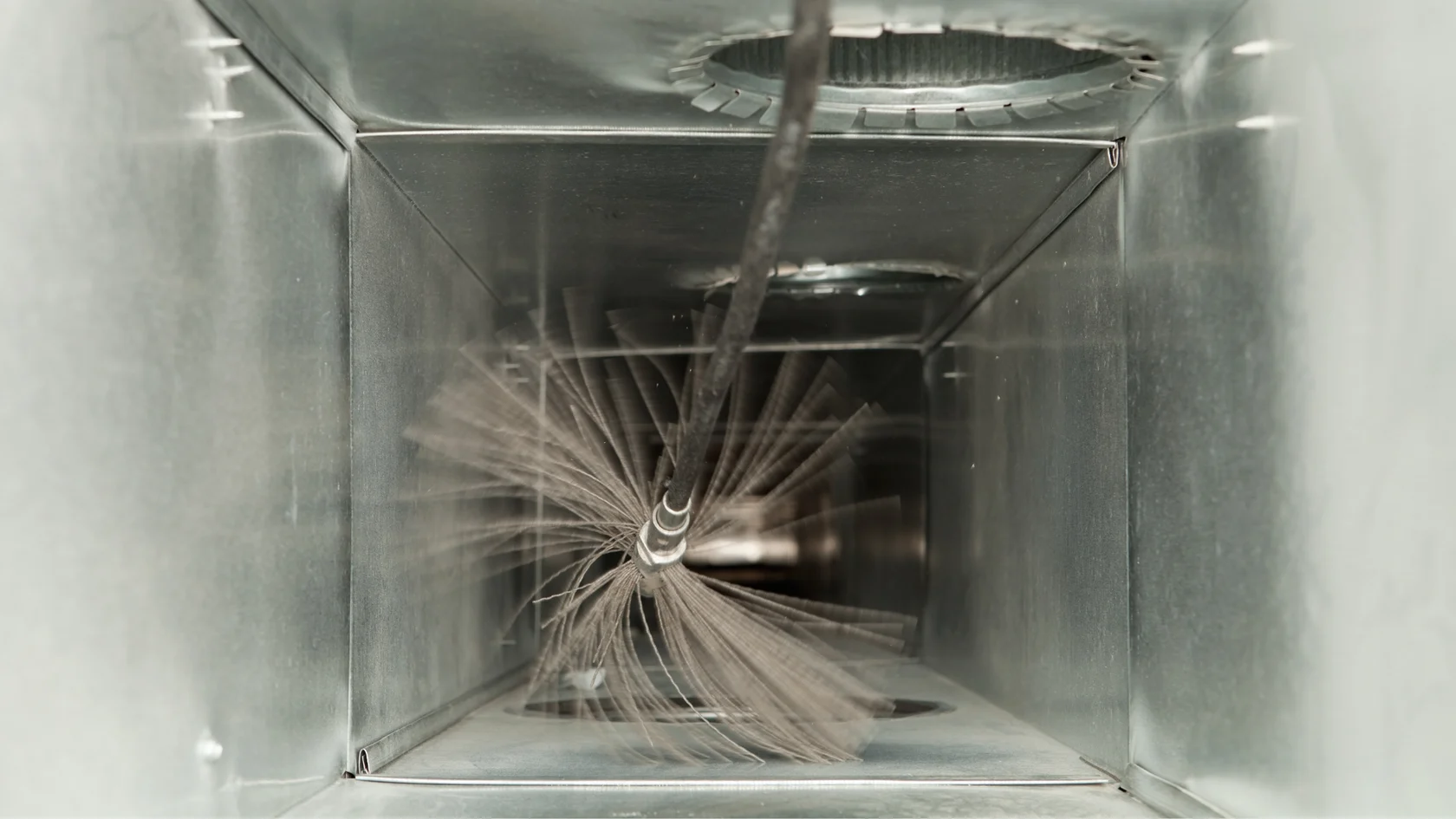 A rotary brush cleaning the interior of a metal air duct