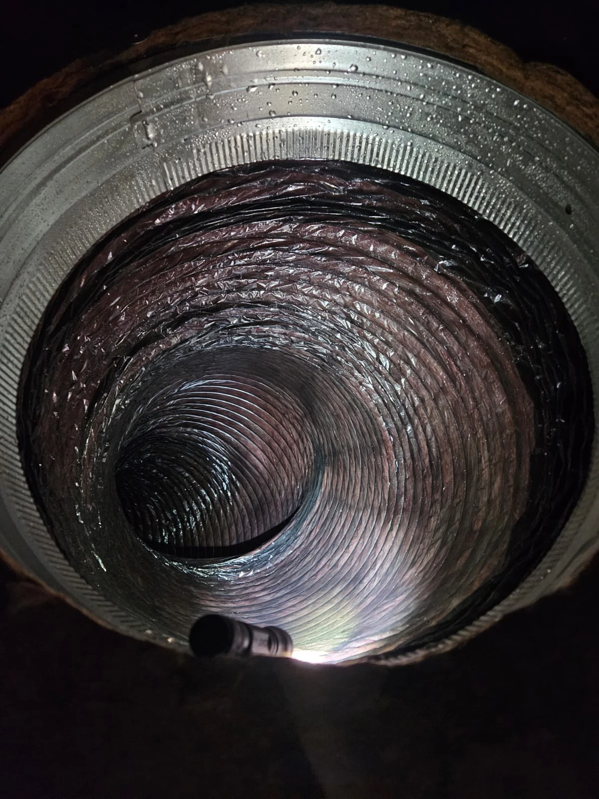 PAC archive photograph looking into a clear flexible duct illuminated by an inspection light